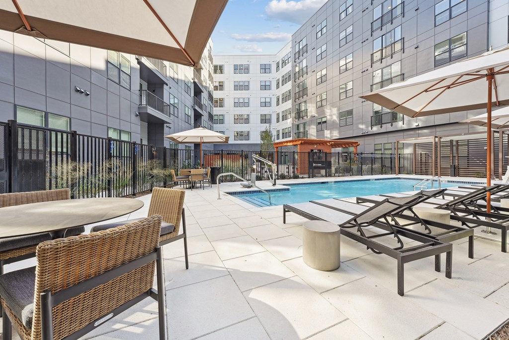 the pool area of a hotel with chairs and umbrellas