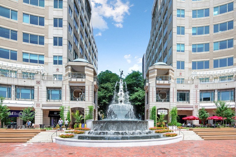a fountain in the middle of a plaza between two buildings
