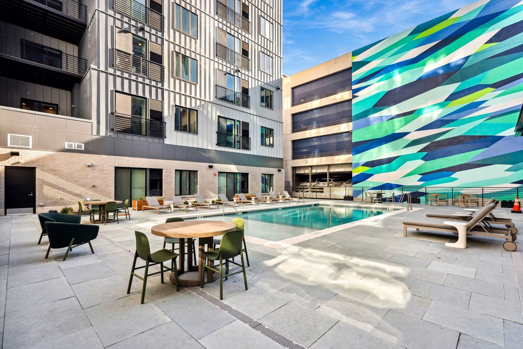 a pool area with a table and chairs in front of a building