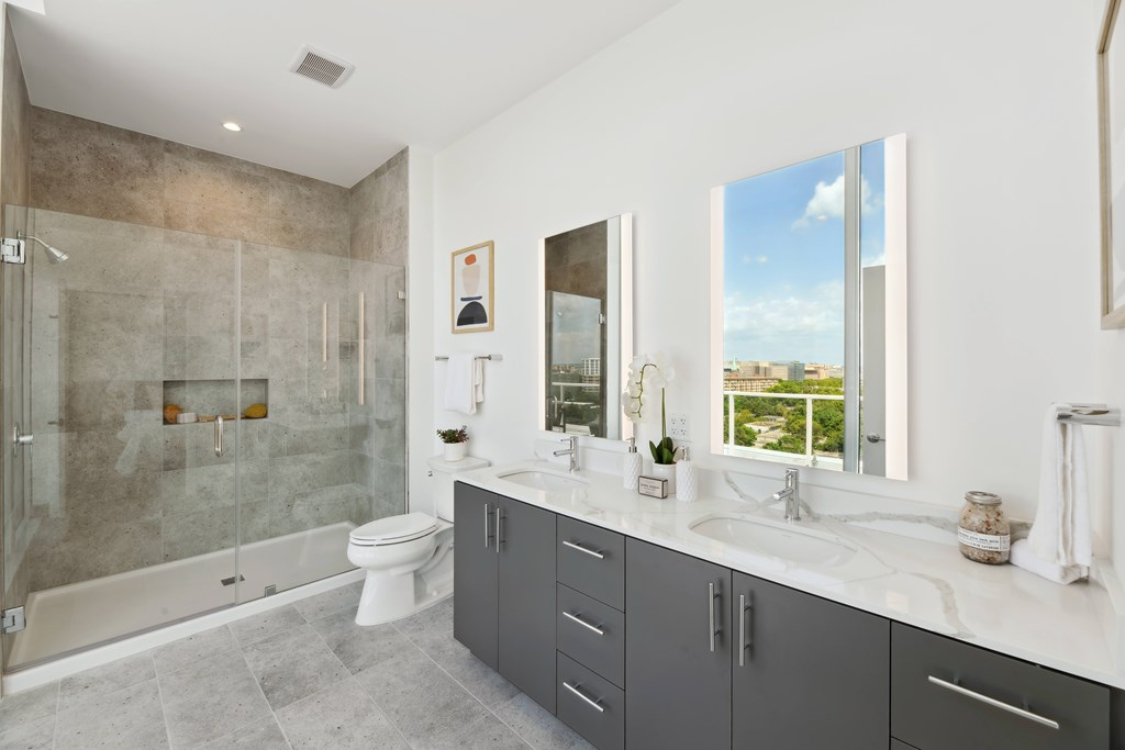 A bathroom with a large mirror, a bathtub, a toilet, and a sink.