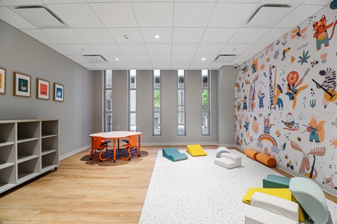 A room with a table, chairs and a wall with drawings on it.