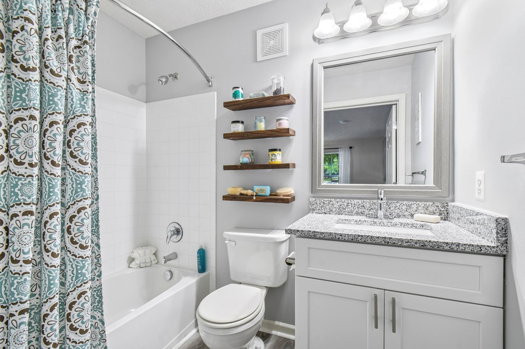 A bathroom with a white toilet, sink, and a shower curtain.