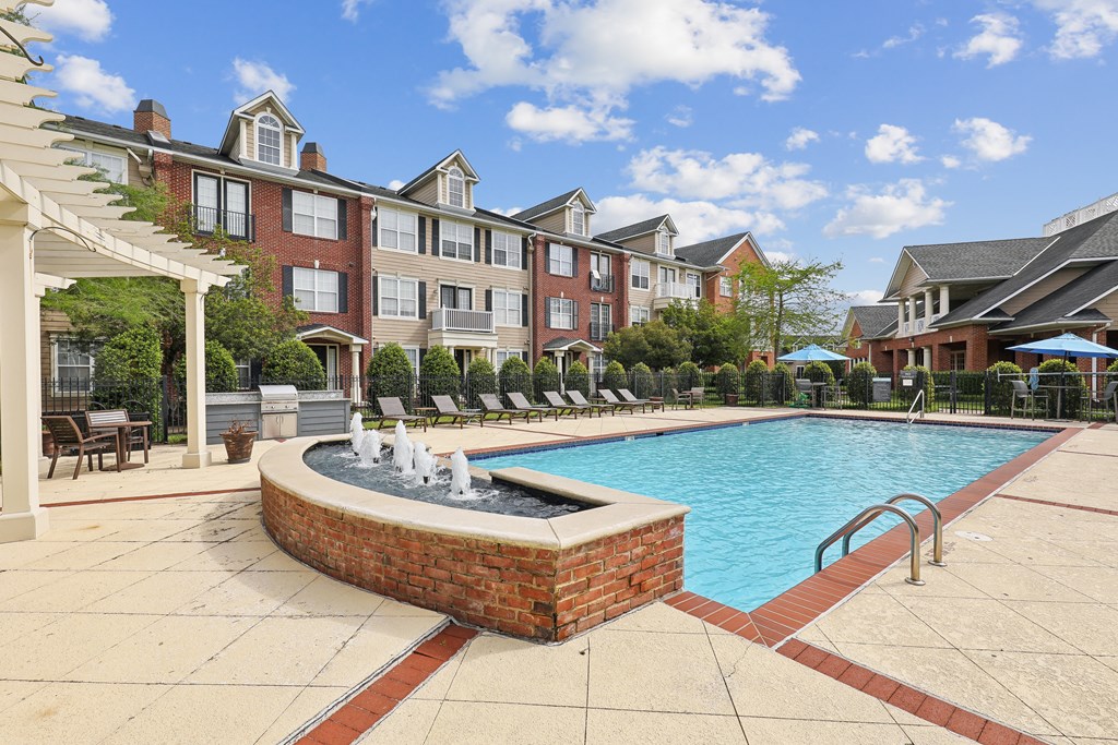 a swimming pool with a fountain in front of an apartment building