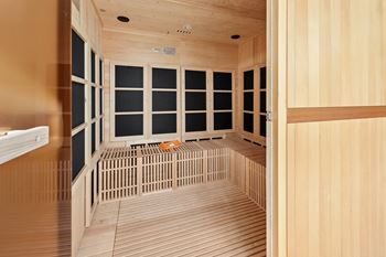 A room with wooden walls and floor and a bench in the middle.