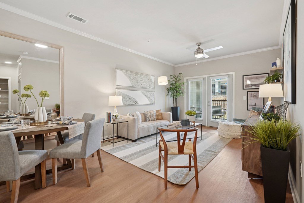 A well-lit, modern living room with a dining area and a kitchen in the background.