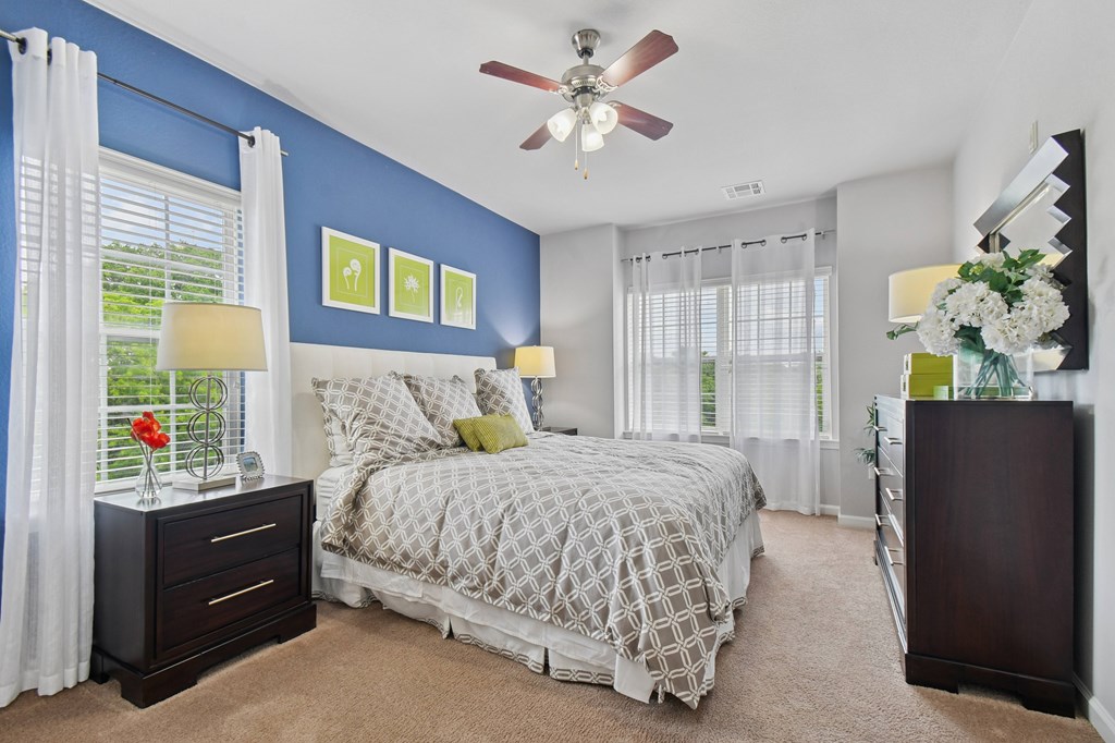 A bedroom with a bed, nightstand, and a ceiling fan.