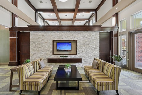A living room with a striped couch and a television on a stone wall.
