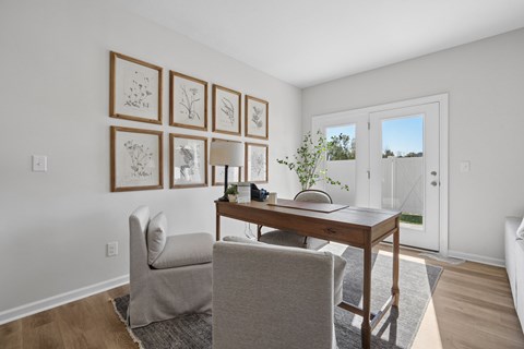 A room with a desk, chair, and pictures on the wall.