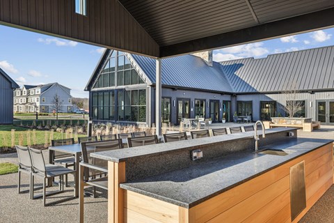 A modern outdoor kitchen with a large island and chairs.
