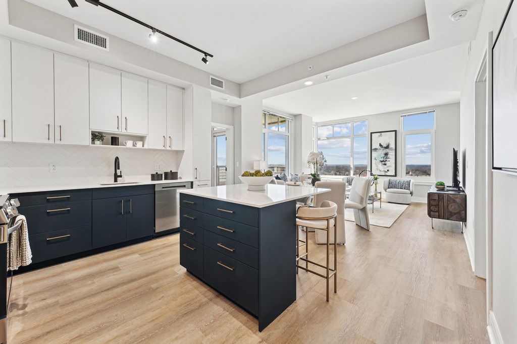 A modern kitchen with dark blue cabinets and a wooden floor.