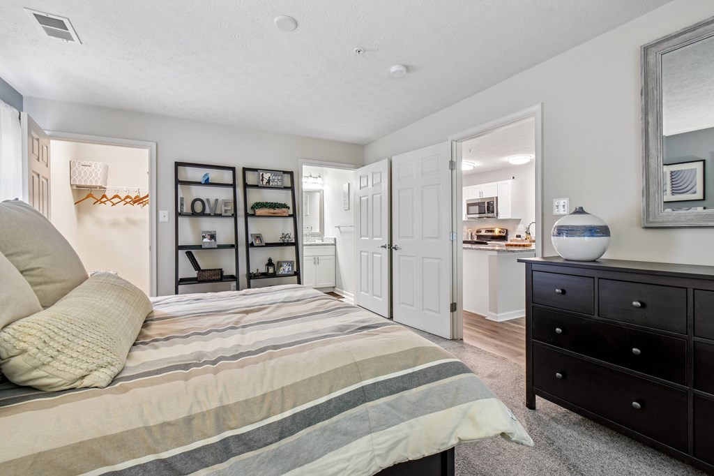 A bedroom with a bed, dresser, and mirror.