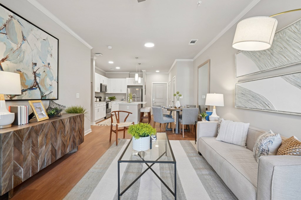 A modern living room with a glass coffee table and a large abstract painting on the wall.