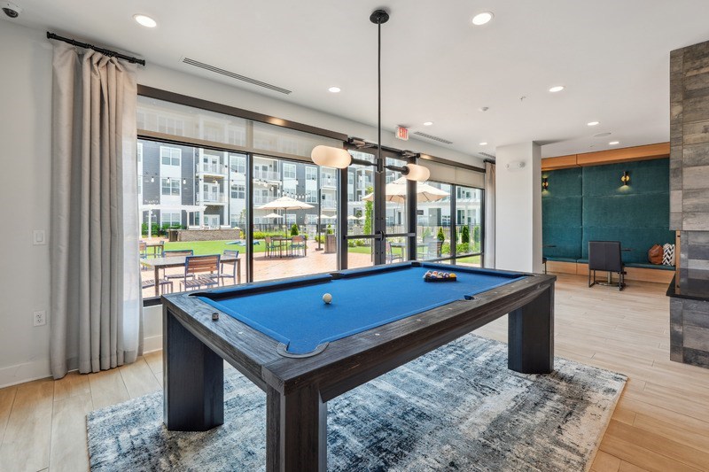A pool table in a room with a view of the outside.
