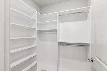 A white walk in closet with shelves and a door.