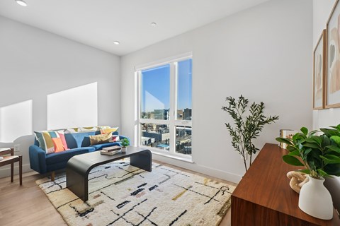 A living room with a blue couch and a large window.