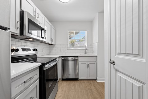 A kitchen with white cabinets and black appliances.