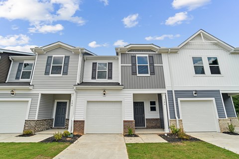 A row of houses with garages and front yards.