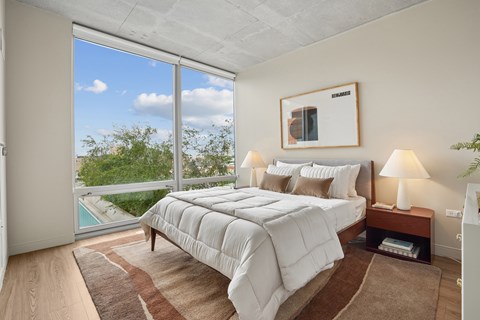 A bedroom with a large bed and a view of the outdoors through a sliding glass door.