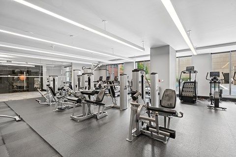 A gym with various exercise machines and a person working out.