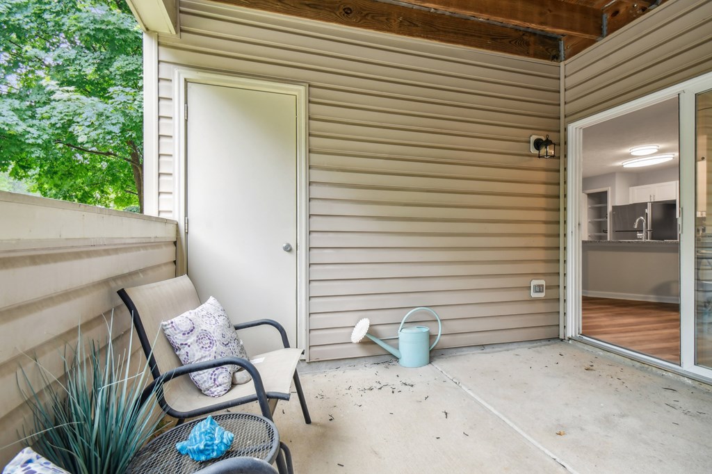 A patio with a chair and a watering can.