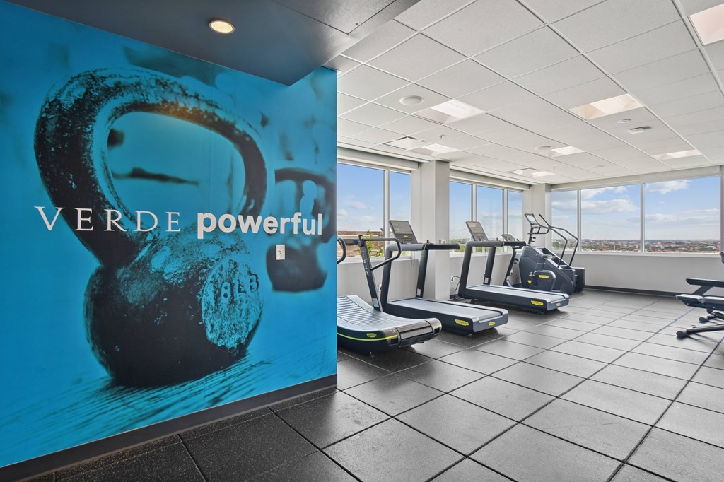 A gym with treadmills and a wall mural that says "VERDE powerful".