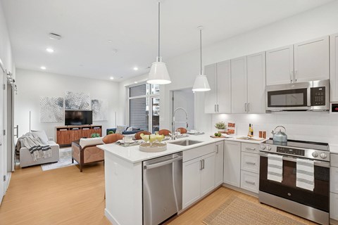 A modern kitchen with a white color scheme and stainless steel appliances.