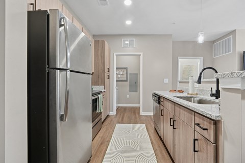 A modern kitchen with a large refrigerator and wooden cabinets.