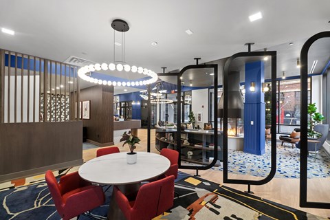 A modern dining area with a round table and red chairs.