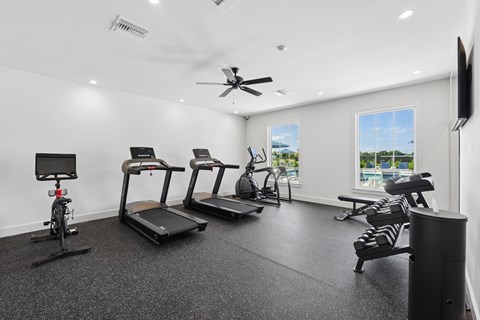 A spacious gym with treadmills, exercise bikes, and a television.