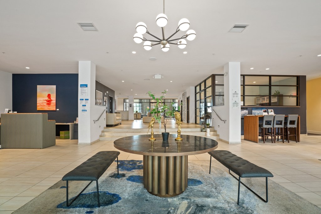 a large lobby with a round table with two benches around it and a chandelier hanging