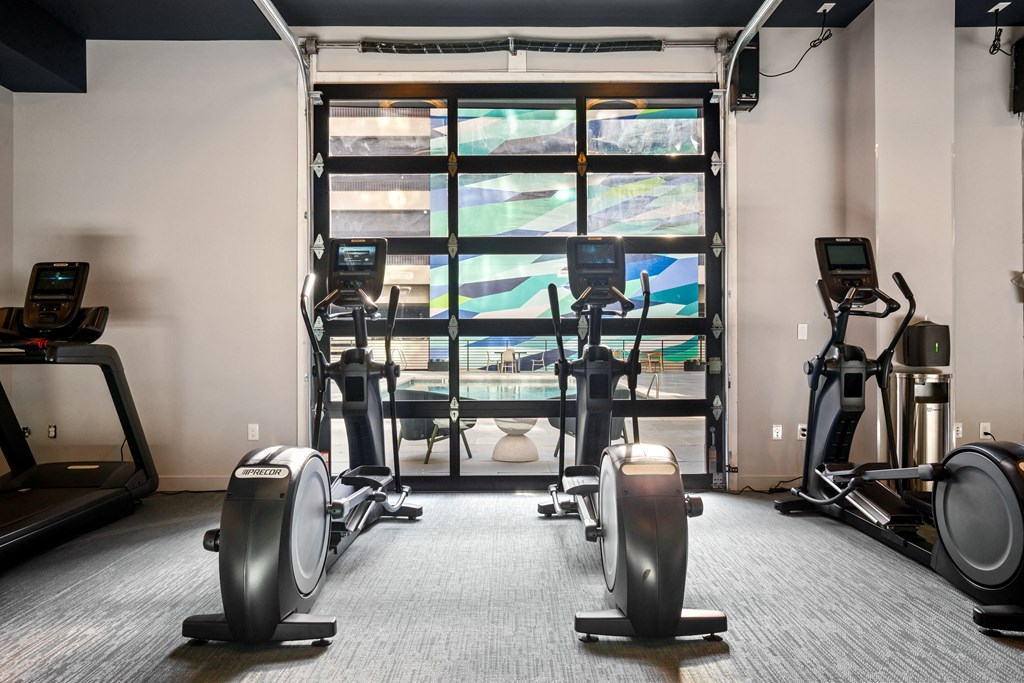a gym with cardio equipment and a window in the back