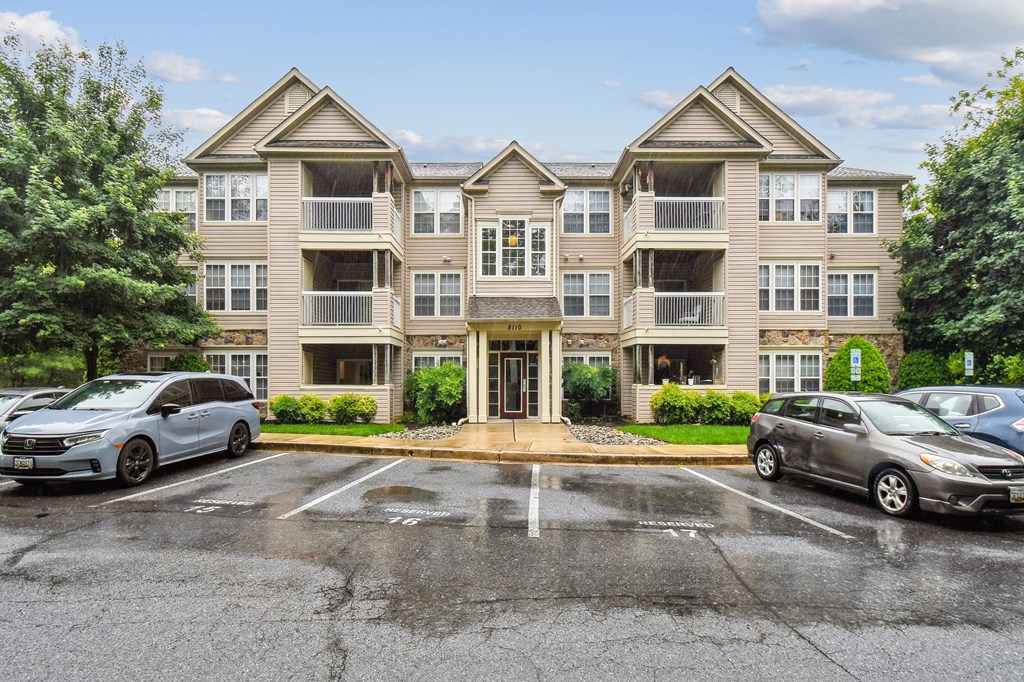 A large apartment complex with a parking lot in front.
