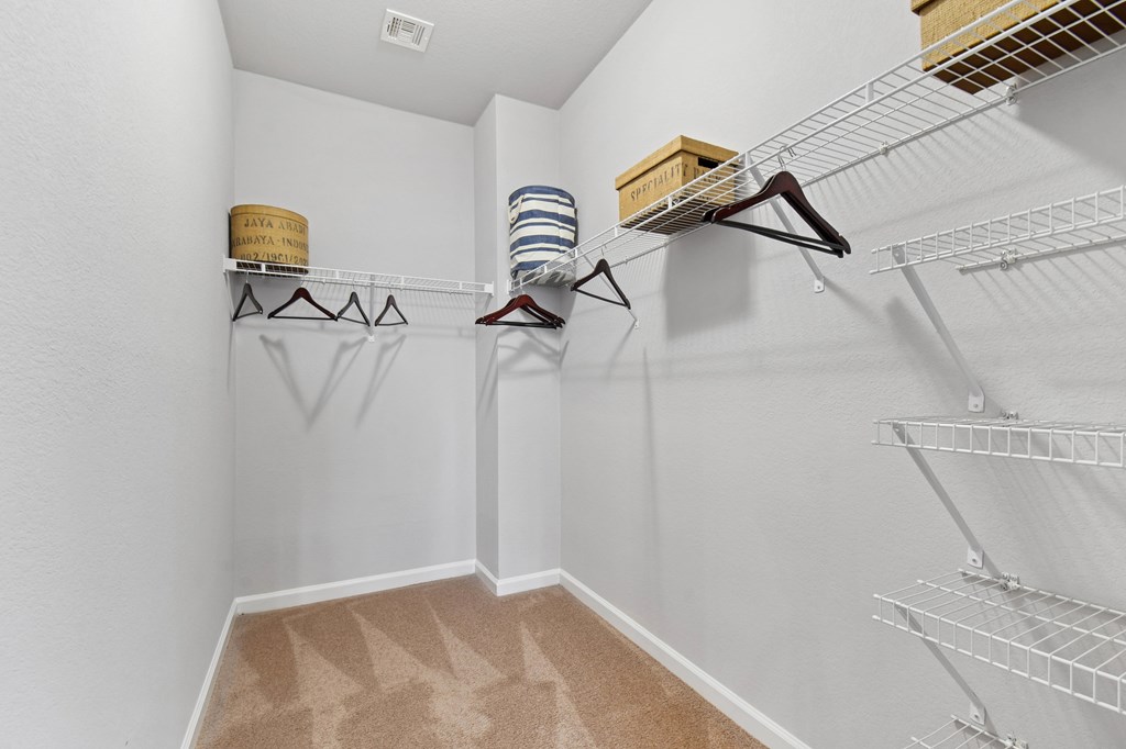 A walk in closet with clothes hanging on racks and shelves.