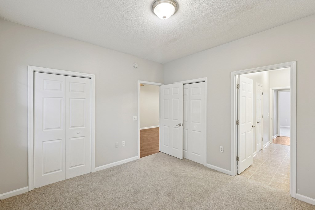 A white room with a carpeted floor and a door on the left.