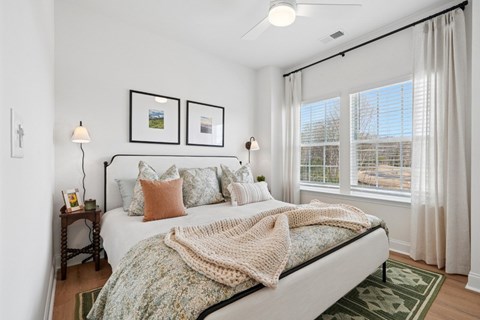 A bedroom with a bed, two lamps, and pictures on the wall.