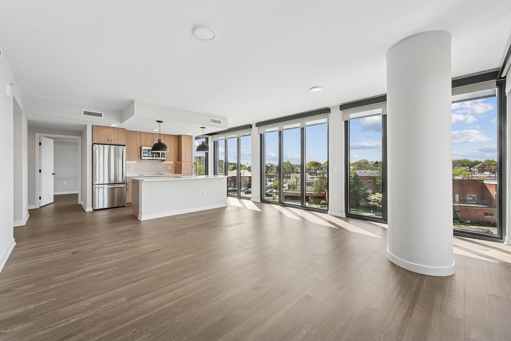 A spacious room with a white column and wooden flooring.