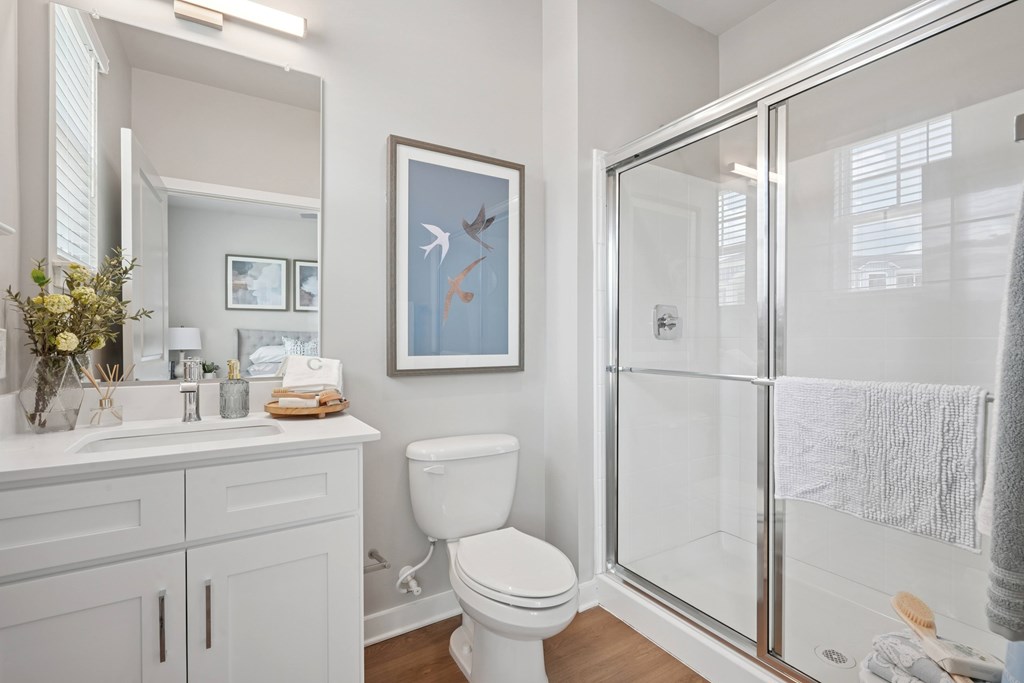 A white bathroom with a toilet, sink, and shower.