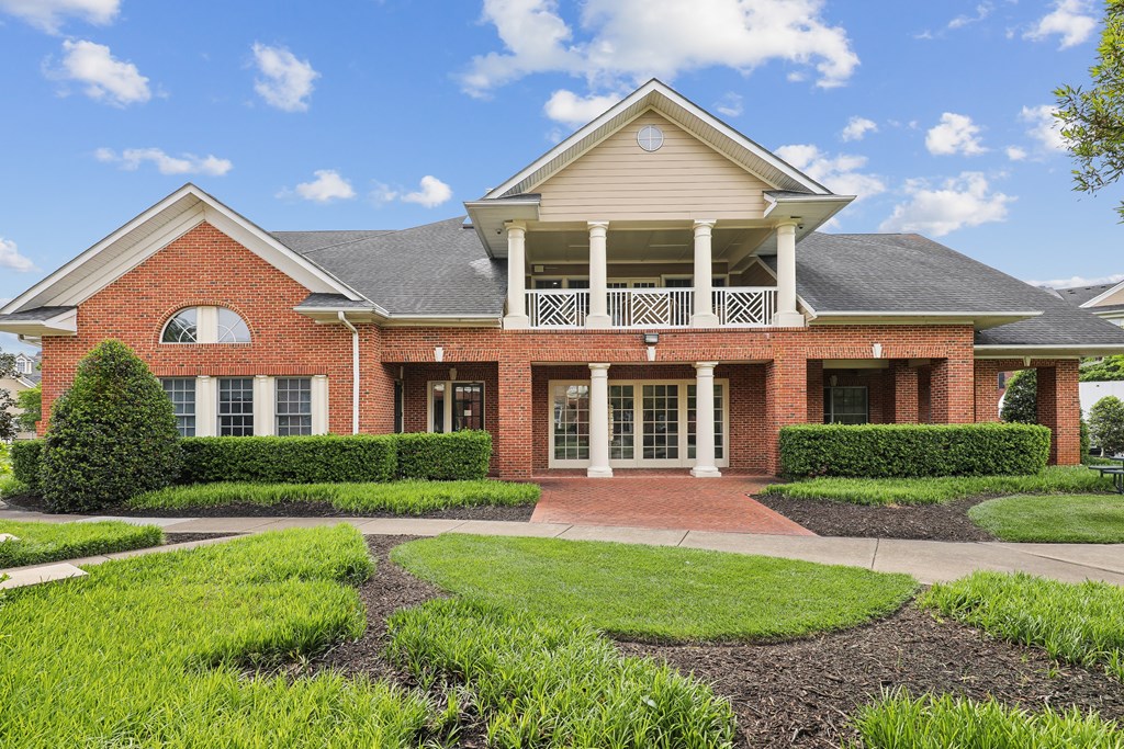 the front of a brick house with a porch and a lawn