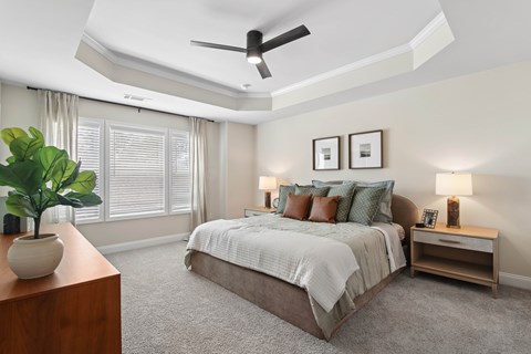 A bedroom with a bed, nightstand, and a plant.