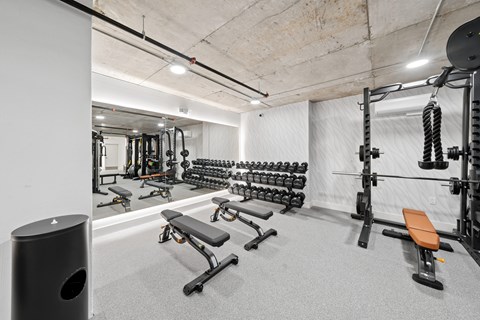 A gym with a variety of equipment including weights and benches.