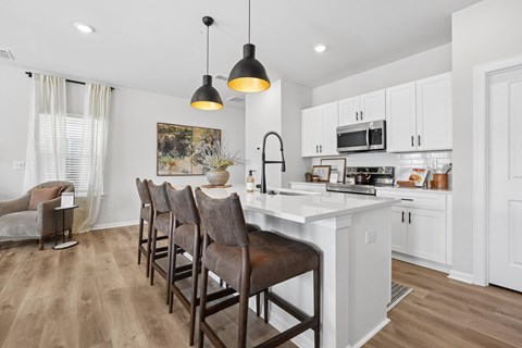 A kitchen with a white countertop and brown chairs.