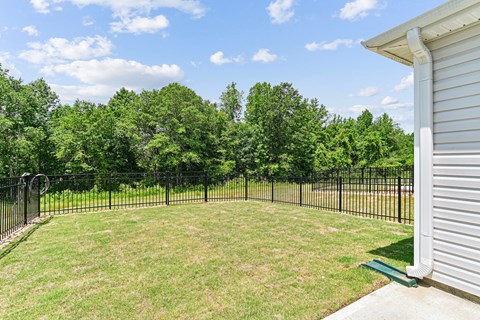 A backyard with a black fence and a green bench.