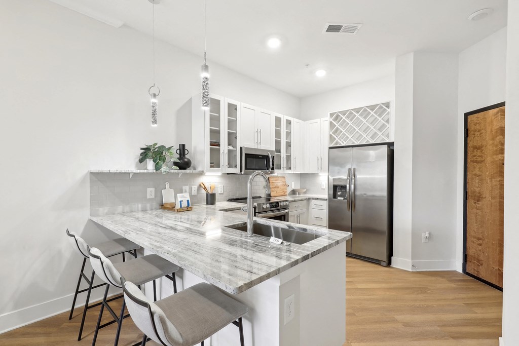 a kitchen with a marble counter top and a stainless steel refrigerator