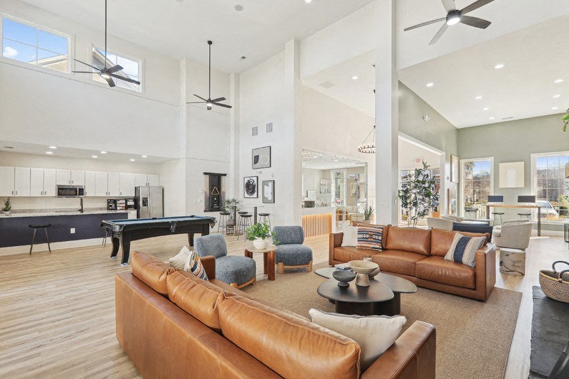 A modern living room with a pool table and a variety of seating options.