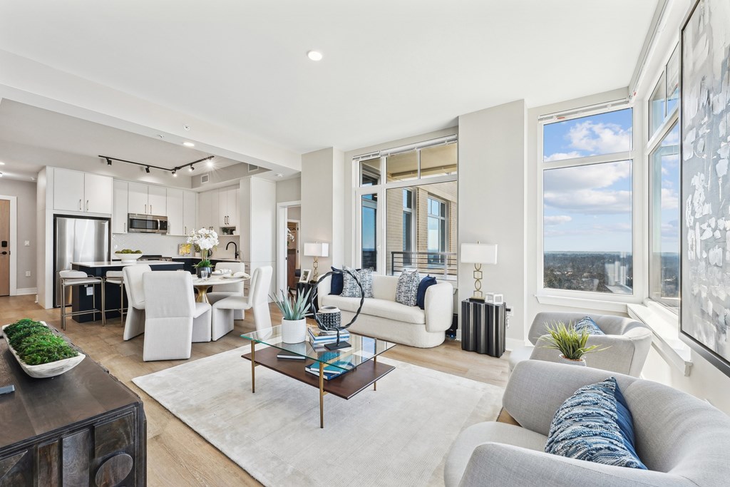 A modern living room with a dining area and kitchen in the background.