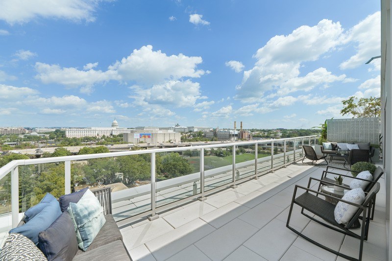 A balcony with chairs and a table overlooking a cityscape.