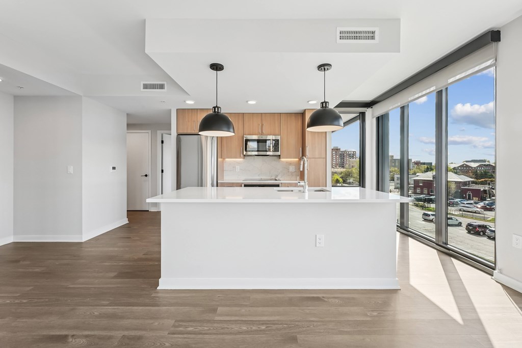 A modern kitchen with a white counter and wooden cabinets.