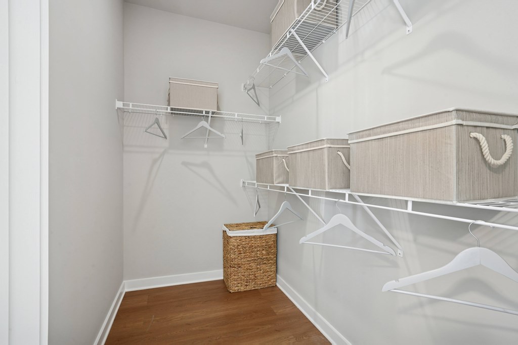 A white closet with a basket on the floor.