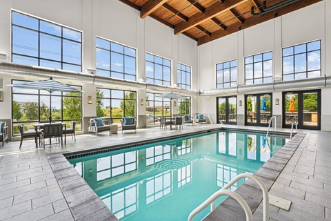 A large indoor swimming pool with a wooden ceiling and a glass wall.