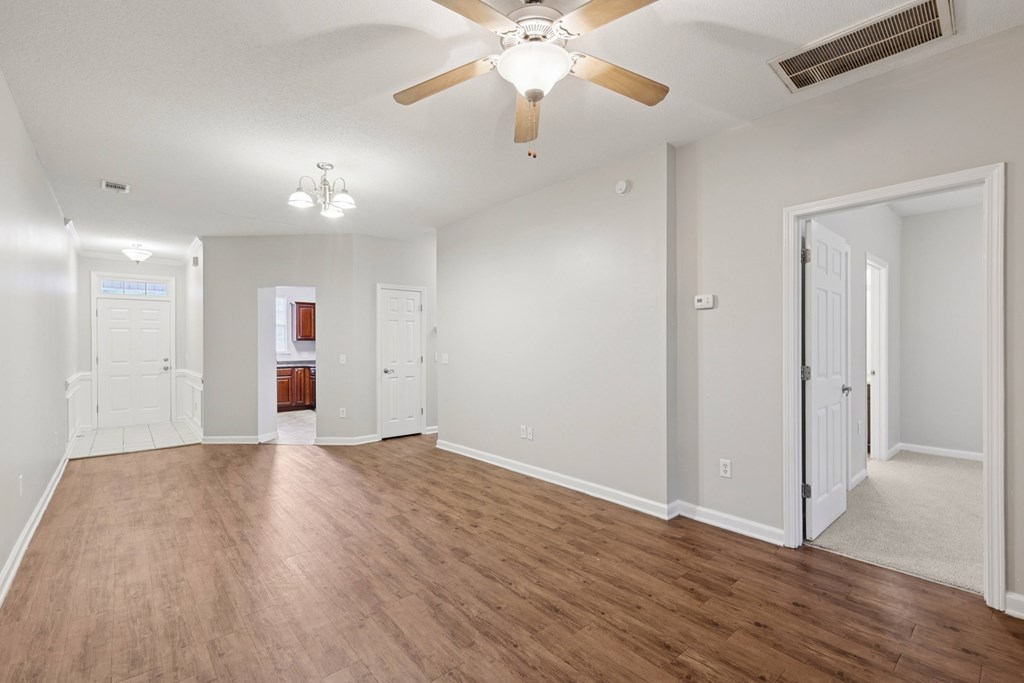 A room with a ceiling fan and wooden floors.